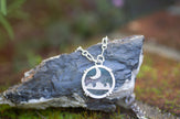 A sterling silver necklace featuring a pendant of opalized wood gemstone with a desert night sky scene. 