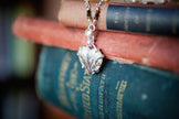 A necklace with a handmade sterling silver pendant featuring a heart shaped dendritic agate and a tiny peridot gemstone. The chain is made from tourmaline, pearl, and peridot beads. 