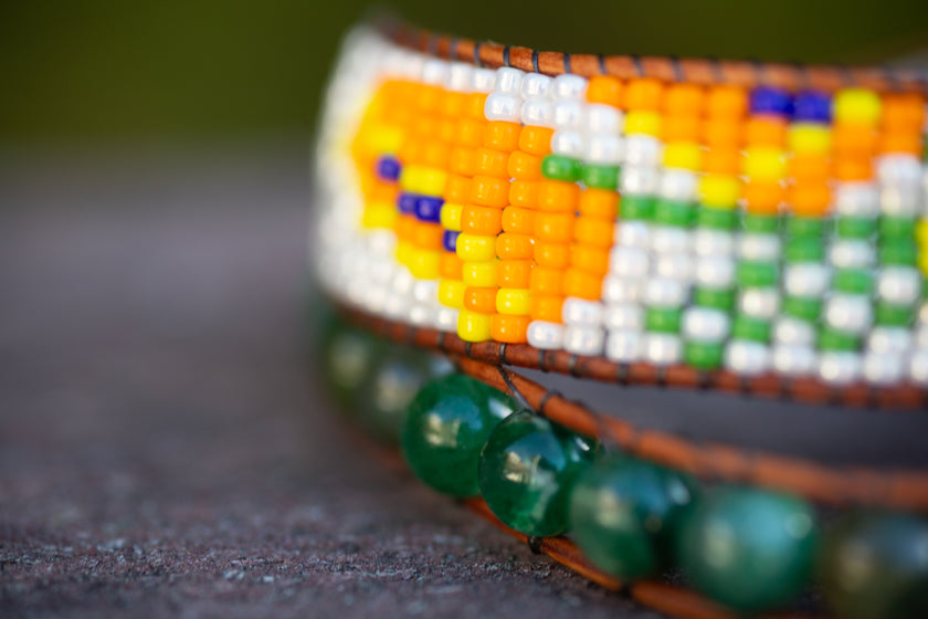 Close up of a California orange poppy beaded wrap bracelet with green mica beads and Miyuki beads. 