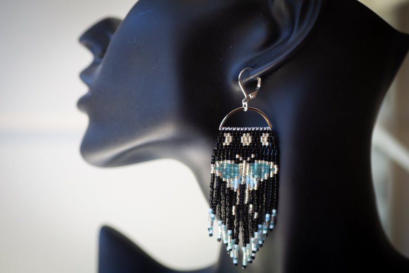 Beaded earring on a mannequin ear with a plain background