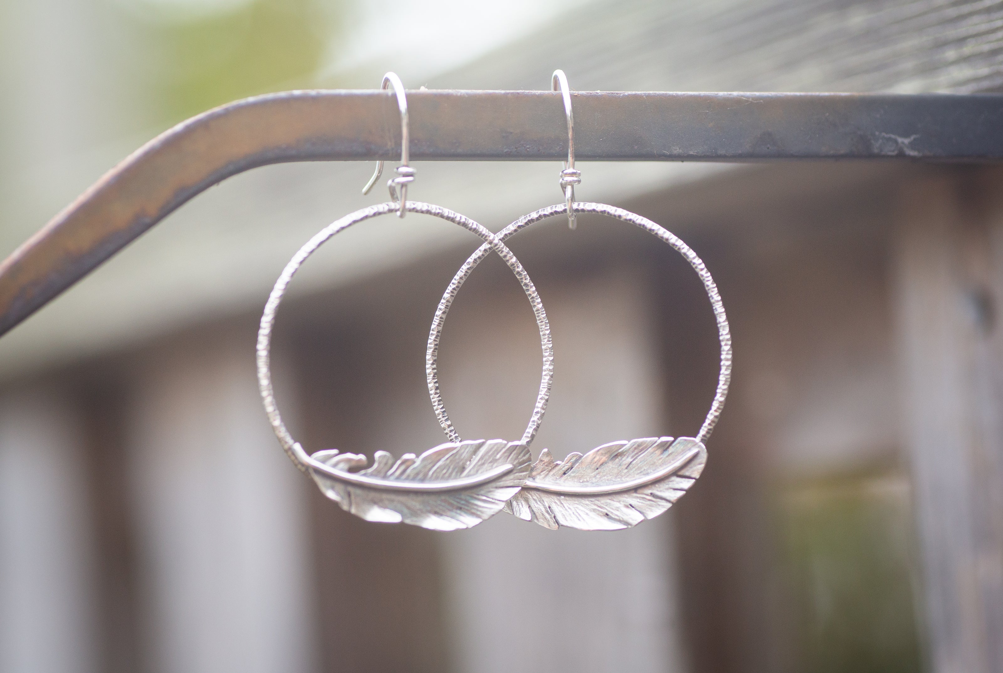 Sterling silver hoop earrings with realistic silver feathers attached.
