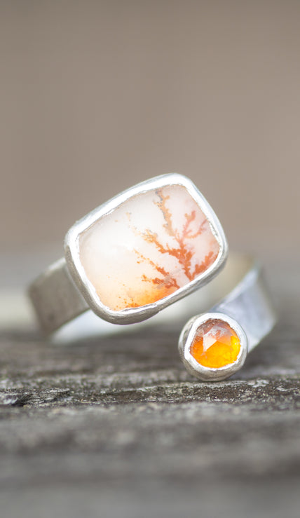 A sterling silver ring with colorful dendritic agate and citrine stones on a wooden surface