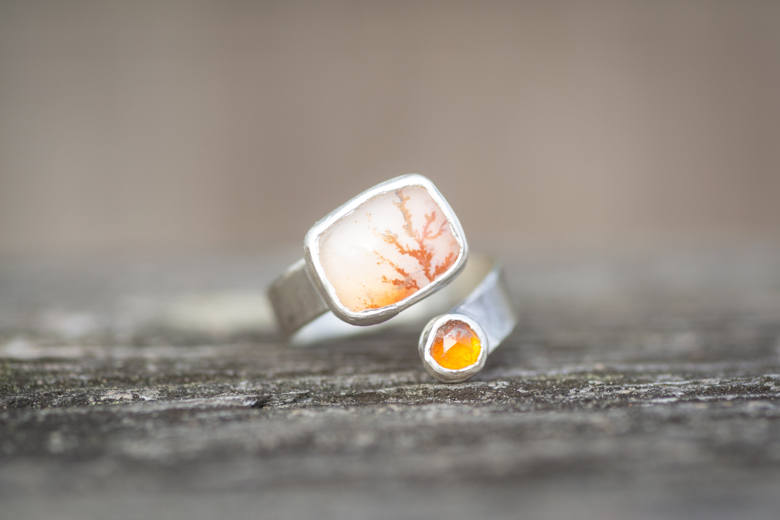 A sterling silver ring with colorful dendritic agate and citrine stones on a wooden surface