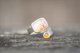 A sterling silver ring with colorful dendritic agate and citrine stones on a wooden surface