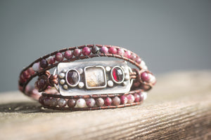 An adjustable leather wrap bracelet with sterling silver, dendritic agate, and garnet gemstones. 