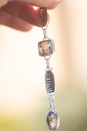 Sterling silver bracelet with textured chain and dendritic agate doublets that is stamped with a quote from Robert Frost's poem Stopping By The Woods.
