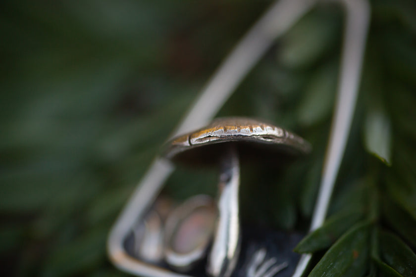 Close up of a handmade sterling silver mushroom pendant. 