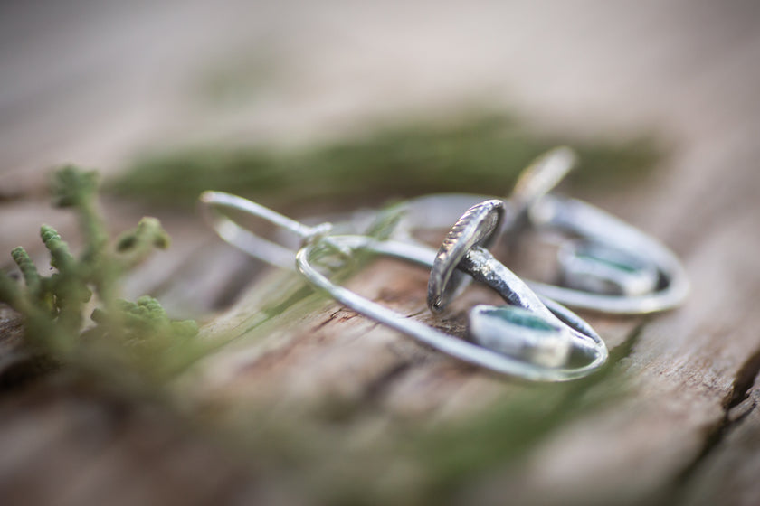 These sterling silver handmade earrings feature tiny fieldcap mushrooms and aventurine stones. The picture is a close up showing the detail of the mushroom cap. 