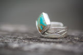 This turquoise and sterling silver ring has a textured band with a wave or mountain pattern. 