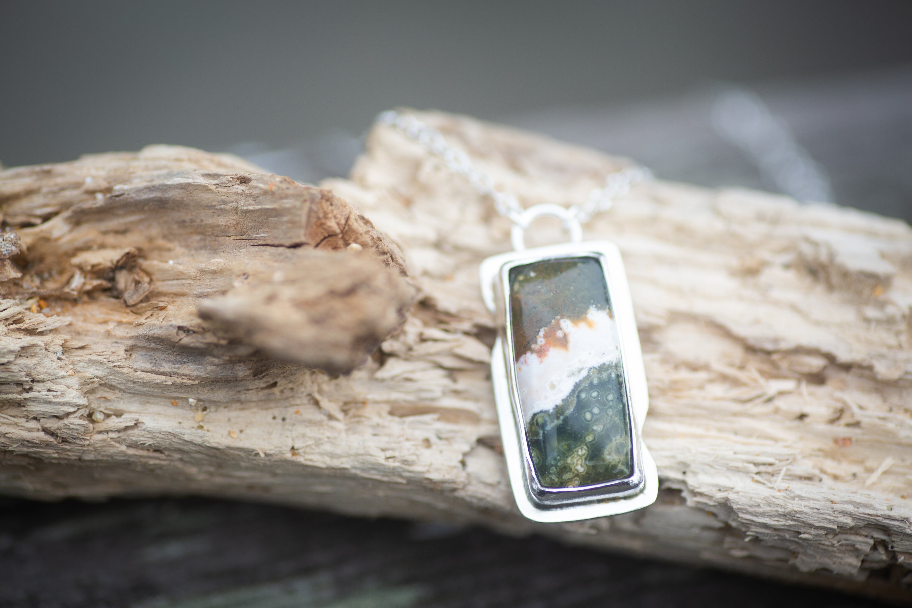A Ocean Jasper and Sterling Silver Necklace that looks like a wave scene or beach scene. 