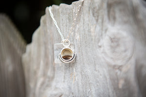Silver necklace with a pendant on a textured stone surface. Inspired by William Wordsworth and the poem Splendour in the Grass. 