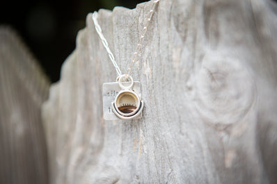 Silver necklace with a pendant on a textured stone surface. Inspired by William Wordsworth and the poem Splendour in the Grass. 